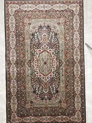 Tappeto persiano hereke seta con medaglione centrale e intricati motivi decorativi floreali su tutto il campo e il bordo del tappeto