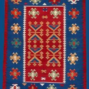 Tappeto Kilim contemporaneo a tessitura piatta, dai colori rossi, blu, arancio e verdi vivaci, e motivi decorativi geometrici uncinati a tutto campo e nello spesso bordo