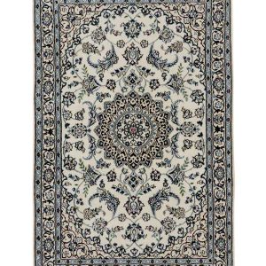 Tappeto persiano nain nola con medaglione centrale blu, intricati dettagli decorativi floreali blu e bianchi su campo bianco e spesso bordo