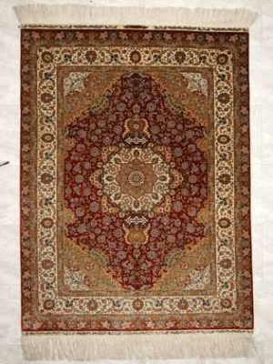 Tappeto hereke seta ouzipek con medaglione centrale bianco e oro su fondo rosso e intricati dettagli decorativi sul doppio bordo bianco e rosso e sul campo e il medaglione del tappeto