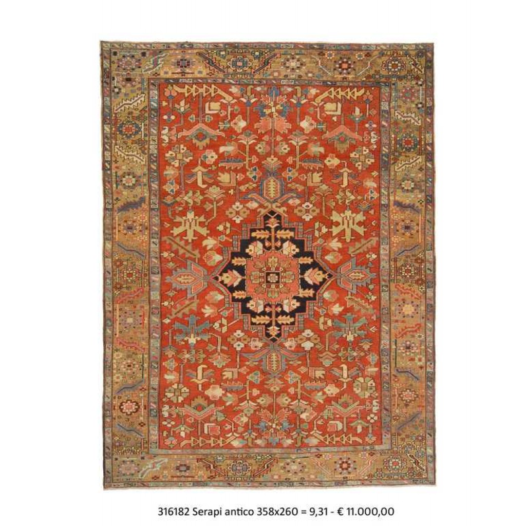 Tappeto persiano serapi con medaglione centrale rosso e blu su campo rosso con dettagli decorativi geometrici stilizzati sul campo e sullo spesso bordo del tappeto