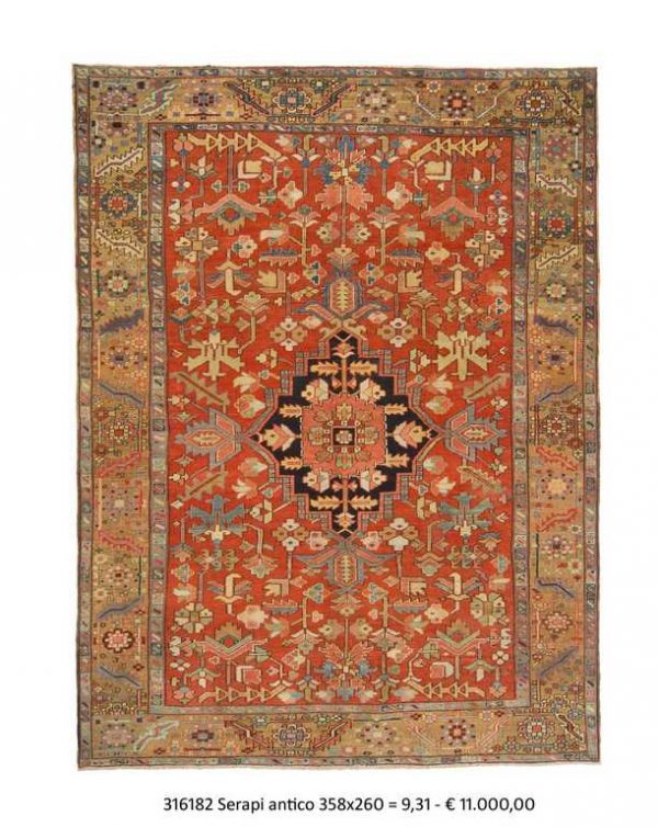 Tappeto persiano serapi con medaglione centrale rosso e blu su campo rosso con dettagli decorativi geometrici stilizzati sul campo e sullo spesso bordo del tappeto