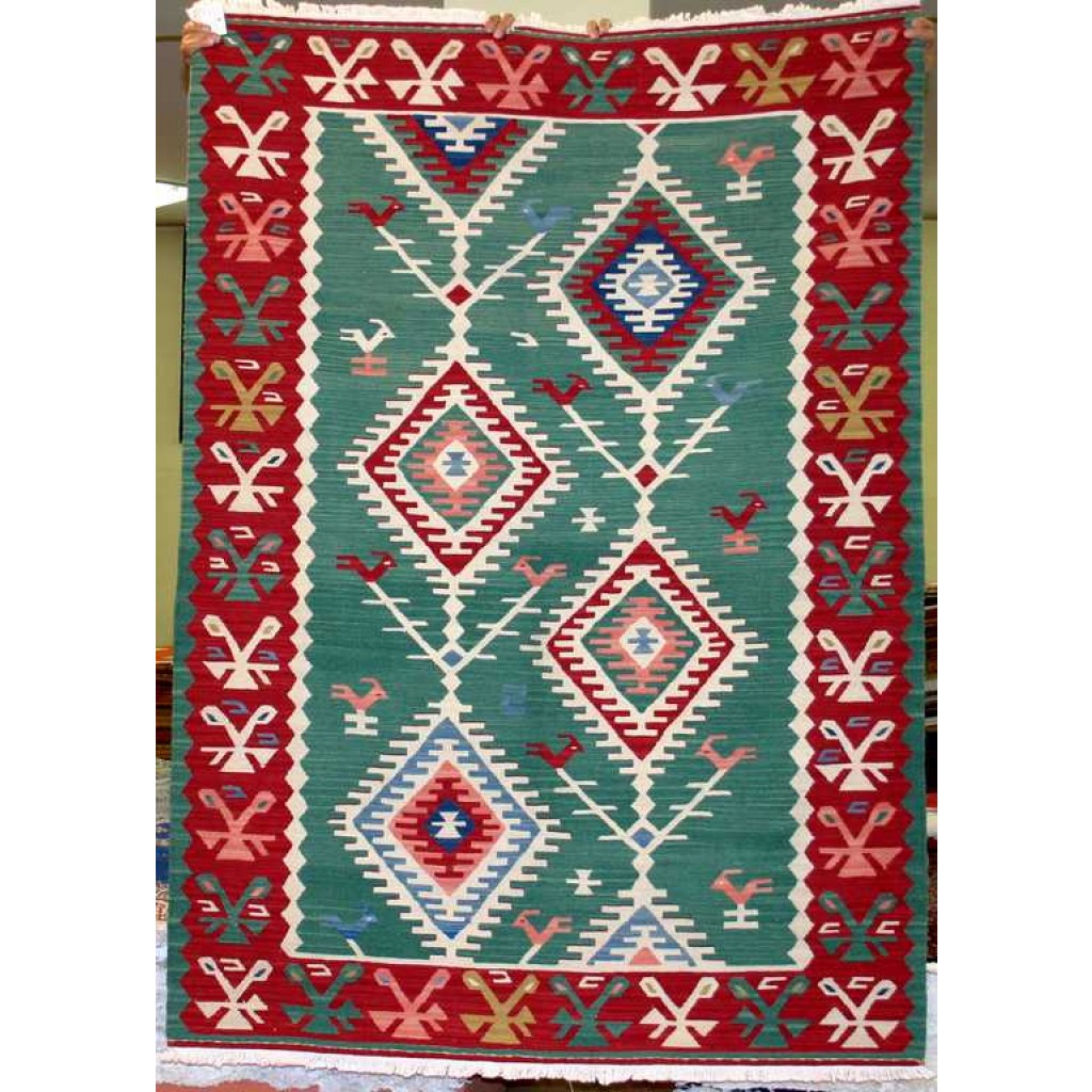 Tappeto contemporaneo kilim lana con motivi decorativi a rombo uncinati su fondo verde e uccelli stilizzati. Spesso bordo rosso decorato con motivi decorativi astratti e lineari