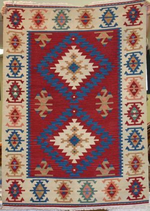 Tappeto contemporaneo kilim lana con doppio medaglione centrale uncinato su fondo rosso e motivi decorativi geometrici astratti su bordo bianco spesso