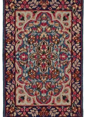Tappeto persiano Kirman, con medaglione centrale decorato a motivi floreali, su sfondo blu e intricati dettagli decorativi sullo spesso bordo blu.