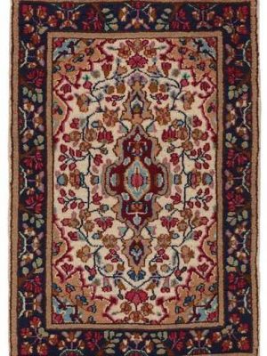 Tappeto persiano Kirman, con medaglione centrale rosso, su sfondo blu e intricati dettagli decorativi sullo spesso bordo blu scuro.