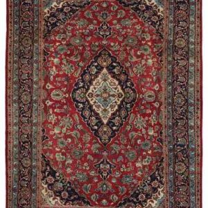Tappeto persiano Mashad con medaglione geometrico centrale bianco e blu, e intricati dettagli decorativi geometrici su sfondo rosso, con spesso bordo blu.