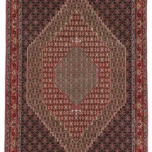 Tappeto persiano Sanandaj con medaglione centrale geometrico a rombo, su sfondo rosso, e motivi decorativi a rombi, herati e boteh a tutto campo