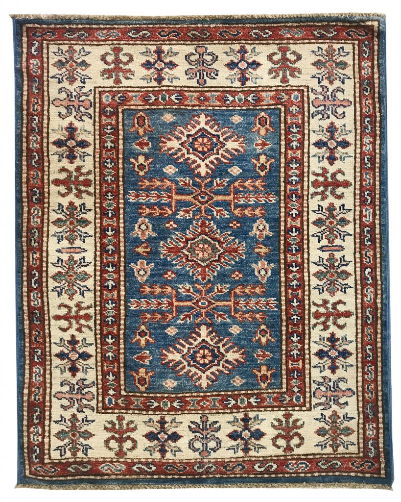 tappeto decorativo lesghi con medaglione centrale su sfondo blu, spesso bordo bianco e rosso e motivi decorativi floreali geometrici