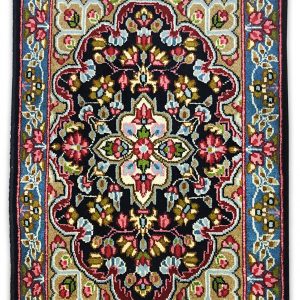 tappeto classico persiano kirma con medaglinoe centrale bianco su sfondo nero e verde, con decorazioni floreali rosse, verdi e azzurre e bordo blu