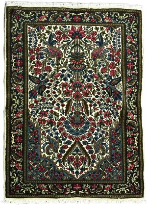 tappeto persiano kirman con medaglione centrale a motivi floreali e animali, su sfondo bianco con piccoli fiori verdi, rosa e azzurri