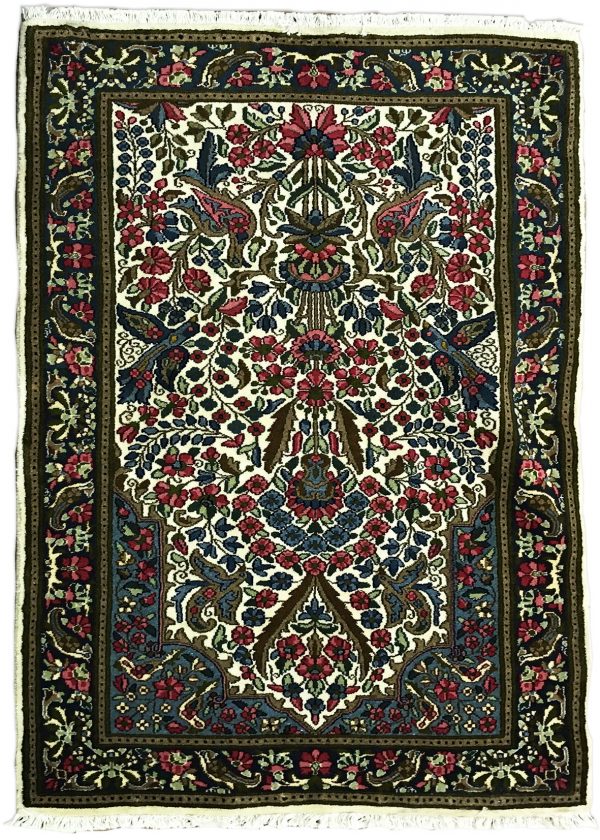 tappeto persiano kirman con medaglione centrale a motivi floreali e animali, su sfondo bianco con piccoli fiori verdi, rosa e azzurri