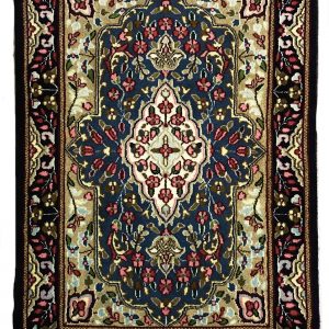tappeto persiano kirman con medaglione centrale bianco a motivi floreali, su sfondo blu con piccoli fiori verdi, rosa e azzurri