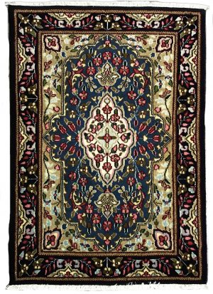 tappeto persiano kirman con medaglione centrale bianco a motivi floreali, su sfondo blu con piccoli fiori verdi, rosa e azzurri