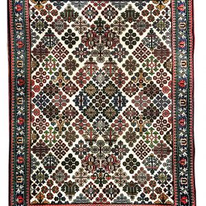 tappeto persiano meyme con motivi geometrici a piccoli medaglioni rossi, blu e verde a tutto campo su sfondo bianco.