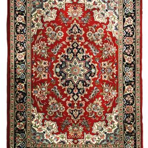 tappeto persiano qum o qom shareza con medaglione centrale nero su sfondo rosso e decorazioni floreali su bordo nero