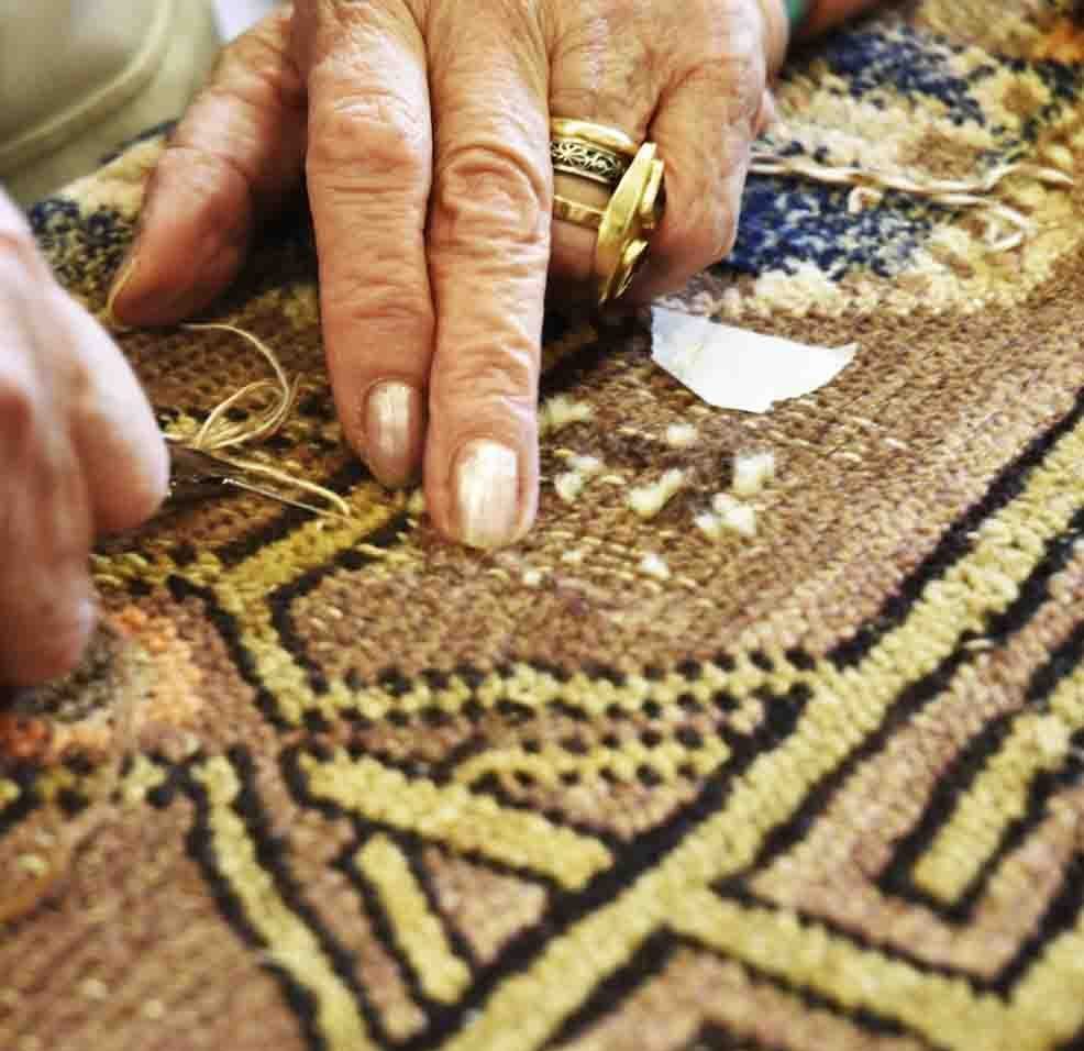 Mani esperte che restaurano le decorazioni di un tappeto