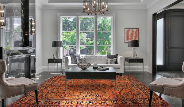 tappeto persiano antico color arancione in soggiorno neoclassico moderno bianco, sotto un tavolino nero e con due consolle ai lati