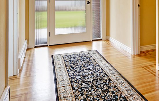 House interior. Entrance hallway with glass door, hardwood floor and  rug. View of piano