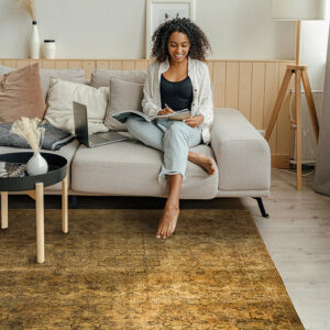 donna seduta su un divano con un tappeto antico: l'arredamento è in stile japandi