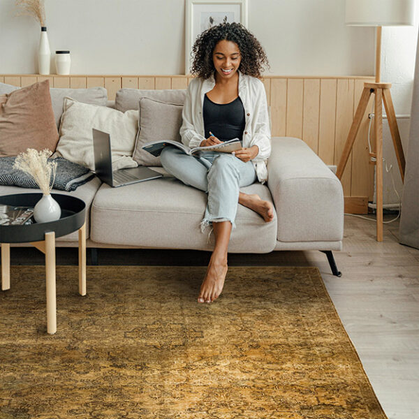 donna seduta su un divano con un tappeto antico: l'arredamento è in stile japandi