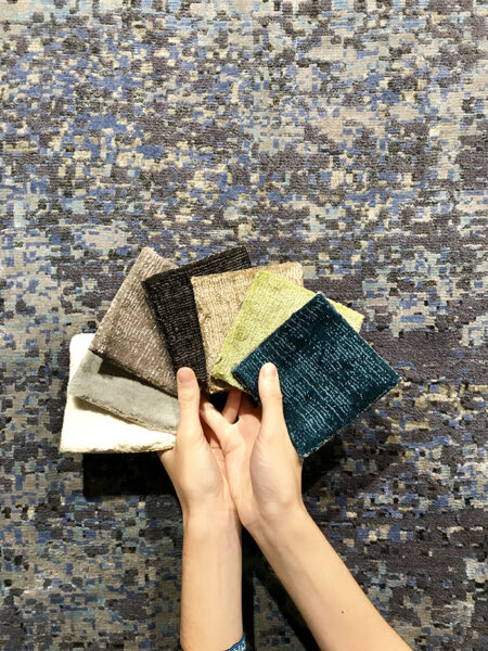 donna con campioni di tessuto su tappeto moderno grigio scuro