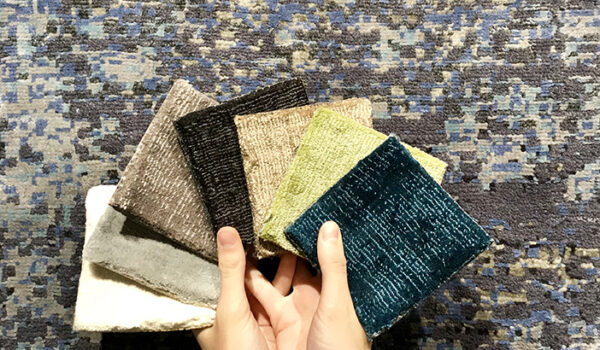 donna con campioni di tessuto su tappeto moderno grigio scuro